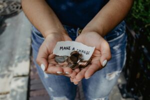 Hands holding coins and a piece of paper with the message 'Make a Change.'